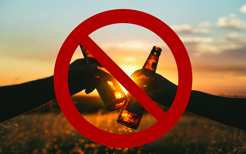 two people holding bottles of beer with a prohibited sign over the top